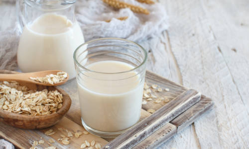 Vegan oat milk, non dairy alternative milk in a glass close up